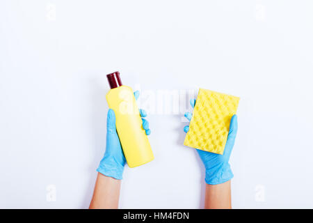 Les femmes dans les mains des gants en caoutchouc bleu jaune tenant une bouteille de détergent et une éponge, vue du dessus Banque D'Images