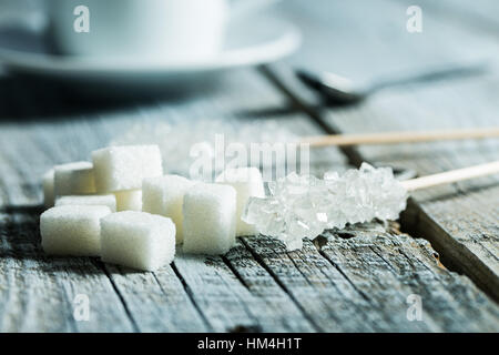 Le sucre cristallisé sur bâtonnet de bois et des morceaux de sucre sur la table en bois. Banque D'Images