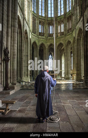 Mont Saint-Michel (Saint Michael's Mount), Normandie, nord-ouest de la France : vue arrière d'un frère sonner la cloche de l'abbaye. Banque D'Images