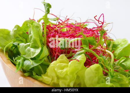 Détail de salade verte avec des germes de betterave et pois dans bol en bois Banque D'Images