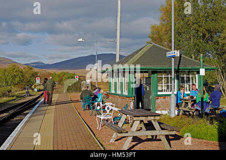 Les gens assis à l'extérieur à des tables de pique-nique sur la plate-forme à Rannoch Railway Station, ayant des rafraîchissements, sur une après-midi ensoleillée d'automne. Le Perthshire. Banque D'Images