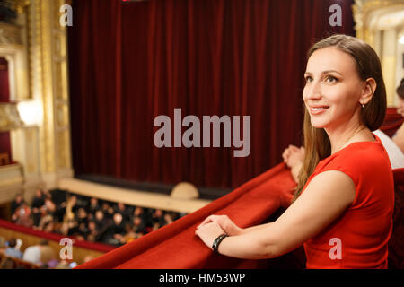 Young smiling woman in dress sitting in theatre Banque D'Images