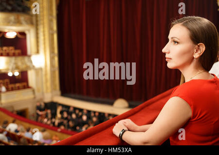 Young smiling woman in dress sitting in theatre Banque D'Images