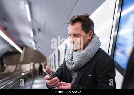 Senior man with smartphone à l'escalator dans le métro Banque D'Images