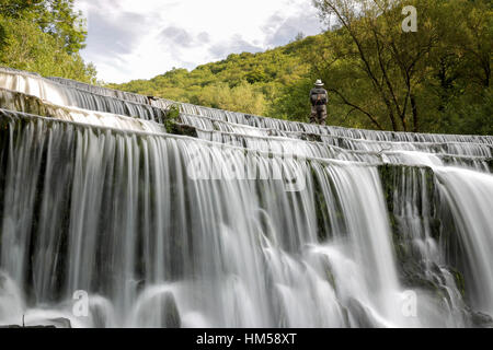 Homme était debout à côté de la rivière en cascade sur la rivière Wye dans le Derbyshire, Angleterre Banque D'Images