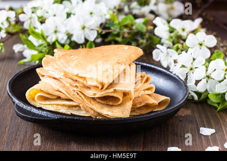 Crêpes maison pliée en triangles sur poêle à fond en fleurs au printemps Banque D'Images