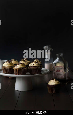 Cupcakes en cakestand avec des bouteilles sur le tableau sur fond noir Banque D'Images