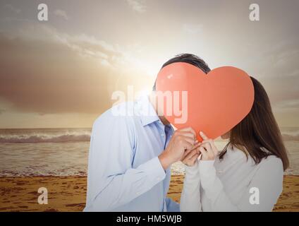 Couple romantique cacher leur visage derrière coeur rouge Banque D'Images