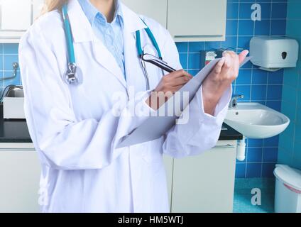 Mid section of female doctor writing on clipboard Banque D'Images