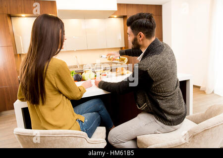 Jeune couple assis dans la cuisine avec son dos et drinking white wine Banque D'Images