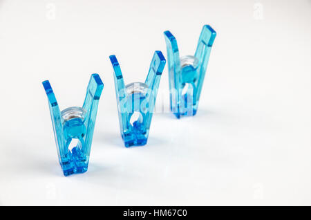 Pinces à linge en plastique bleu sur fond blanc. Banque D'Images