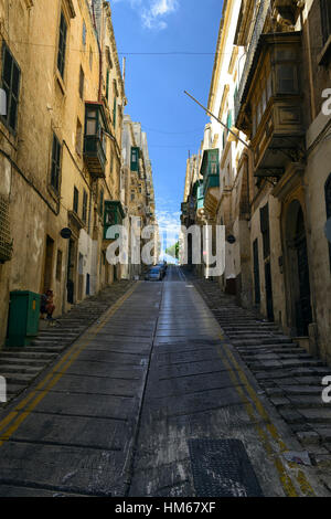 Côté vallonné de la colline raide tout droit rue rues étroites traditionnelles en bois coloré balcon espace encombré road Valletta malte Banque D'Images