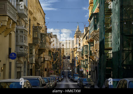 Côté vallonné de la colline raide tout droit rue rues étroites traditionnelles en bois coloré balcon espace encombré road Valletta malte Banque D'Images