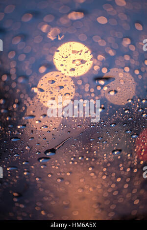 Gouttes de pluie sur la fenêtre avec la lumière de la route, saison des pluies bokeh abstract background,goutte d'eau sur la vitre, la pluie tempête nuit voiture concept. Banque D'Images