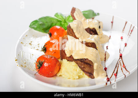 La viande de mouton au four avec sauce crémeuse, purée de pommes de terre et tomates cerises Banque D'Images