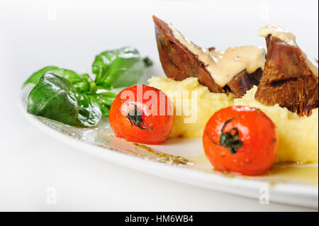 La viande de mouton au four avec sauce crémeuse, purée de pommes de terre et tomates cerises Banque D'Images