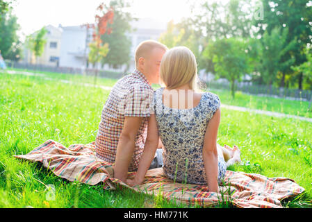 Couple Jeune homme et femme assis sur un banc de parc en serrant le ruban, déclaration d'amour, doux câlin, concept famille d'événements, mariage heureux. Mode de vie dans la ville. À l'extérieur. Banque D'Images