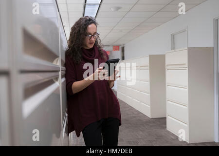 Young woman using digital tablet in corridor Banque D'Images