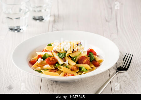 La Tomate et bacon pâtes Penne sur table en bois blanc Banque D'Images