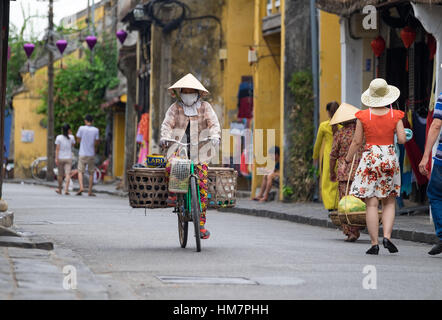 Femme non identifiée avec un panier pour vendre des aliments sur rue. Hoi An, Vietna Banque D'Images