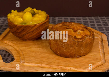 La relish Piccalilli dans un bol en bois sur une planche. Banque D'Images