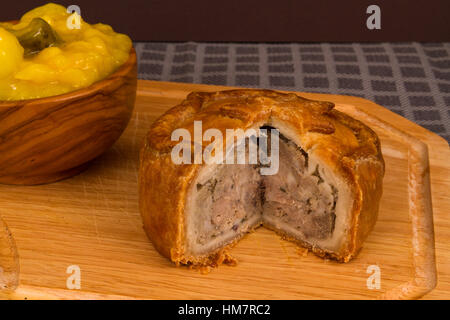 La relish Piccalilli dans un bol en bois sur une planche. Banque D'Images