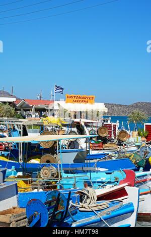 La pêche traditionnelle grecque des bateaux amarrés dans le port avec une taverne à l'arrière, Elounda, Crète, Grèce, Europe. Banque D'Images