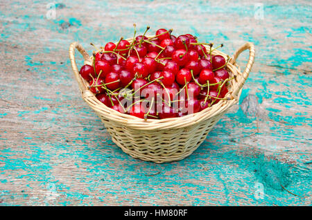 Panier en osier plein de fruits cerise d'été sur table de jardin Banque D'Images