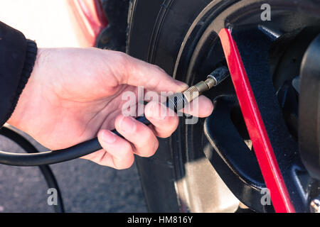 L'homme de la connexion compresseur d'air pour les pneus de voiture pour contrôler la pression de l'air et le remplissage avec de l'air Banque D'Images