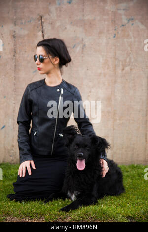 Portrait de jeunes femmes adultes en blouson de cuir avec chien noir Banque D'Images