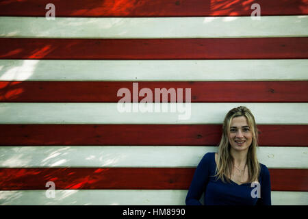 Portrait of Mid-Adult Woman contre mur avec rayures rouges et blanches Banque D'Images