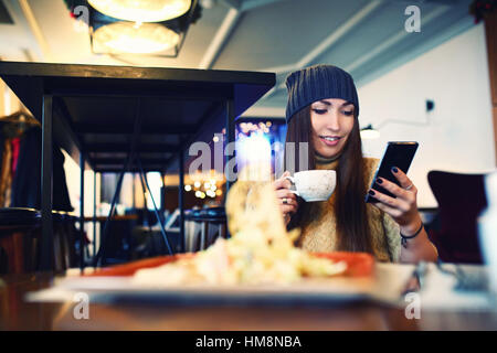 Portret de jeunes femmes Lecture des SMS sur le téléphone dans le café. Tonned. Focus sélectif. Banque D'Images