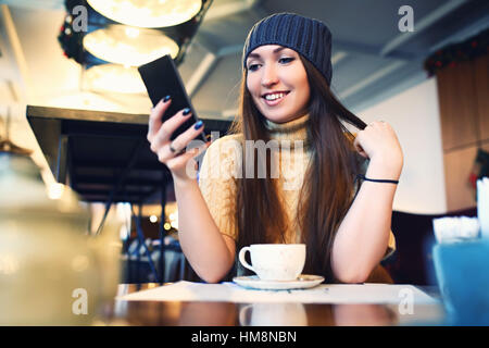 Portret de jeunes femmes Lecture des SMS sur le téléphone dans le café. Tonned. Focus sélectif. Banque D'Images