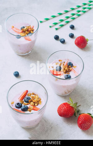 Bleuet fraise smoothies sains et garni de petits fruits frais, de muesli et de feuille de menthe avec tube cocktail Banque D'Images