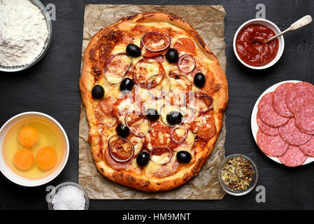 Des pizzas et des ingrédients sur fond sombre, vue du dessus Banque D'Images