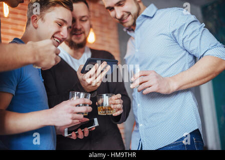 Cheerful vieux amis communiquer les uns avec les autres et du téléphone, verres de whisky dans un pub. Divertissement concept de vie. Connexion Wi-Fi au réseau local connecté au bar de la table de concertation Banque D'Images