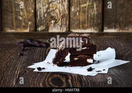 Brownies au chocolat maison avec fromage à la crème sur du papier sulfurisé sur table en bois rustique Banque D'Images