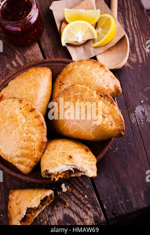 Boulangerie maison empanadas végétarien, légumes farcis de style latino-américain pie avec compotée de choux, carottes, oignons, tomates sur l'arrière en bois rustique Banque D'Images