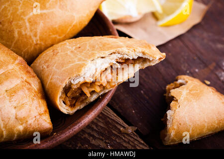 Boulangerie maison empanadas végétarien, légumes farcis de style latino-américain pie avec compotée de choux, carottes, oignons, tomates sur l'arrière en bois rustique Banque D'Images