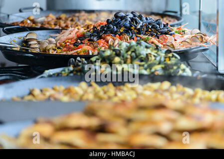 Sélection de plats cuisinés prêts à l'emploi, avec une poêle à paella sur un marché de Saint-Palais-sur-Mer, Charente-Maritime, France, en été. Banque D'Images