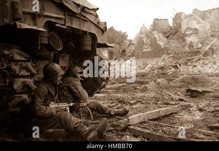Avec des obus allemands crier les frais généraux, les fantassins américains chercher refuge derrière un tank. Dans l'arrière-plan peut être vu les ruines de la ville de Geich, l'Allemagne, qui est encore à l'artillerie lourde. 11 Décembre, 1944. Roberts. (Armée) NARA DOSSIER #  : 111-SC-197261 LIVRE Guerres et conflits #  : 1090 Banque D'Images