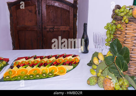 Composition de fruits et couper le verre demijohn vin couché pour l'osier. Sur une table laden avec un restaurant, avec des raisins, des figues, de figuiers de barbarie et de feuilles. Un Banque D'Images