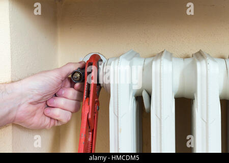 Au travail plombier installation d'une vanne thermostatique sur un radiateur Banque D'Images