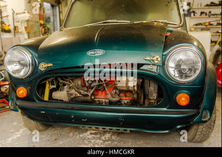 Un vieux/classic green Austin Mini Cooper en partie démonté/dépouillé vers le bas pour la restauration dans un garage/atelier. Banque D'Images