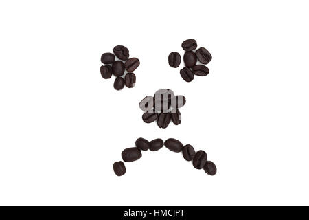 Un triste visage fait avec des grains de café sur fond blanc Banque D'Images