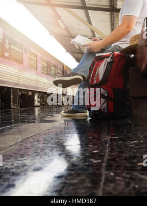 Voyageur asiatique homme avec effets personnels en attente de voyager par train à la gare de Chiang Mai, Thaïlande. Banque D'Images