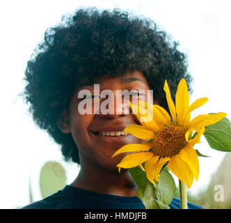 Jeune garçon sourit joyeusement tout en maintenant un tournesol à la main qui a grandi Banque D'Images