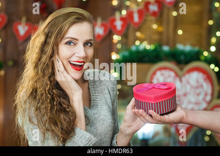 L'homme donne un don d'une jeune fille blonde aux cheveux bouclés. teens fêter la Saint-Valentin Banque D'Images