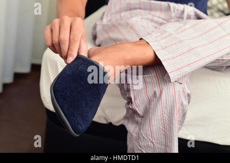 Libre d'un jeune homme de race blanche en pyjama assis sur le bord du lit de mettre ou non dans une paire de chaussons chaud Banque D'Images