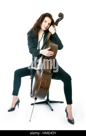 Belle brune femme assise avec de vieux brown violoncelle en studio against white background Banque D'Images